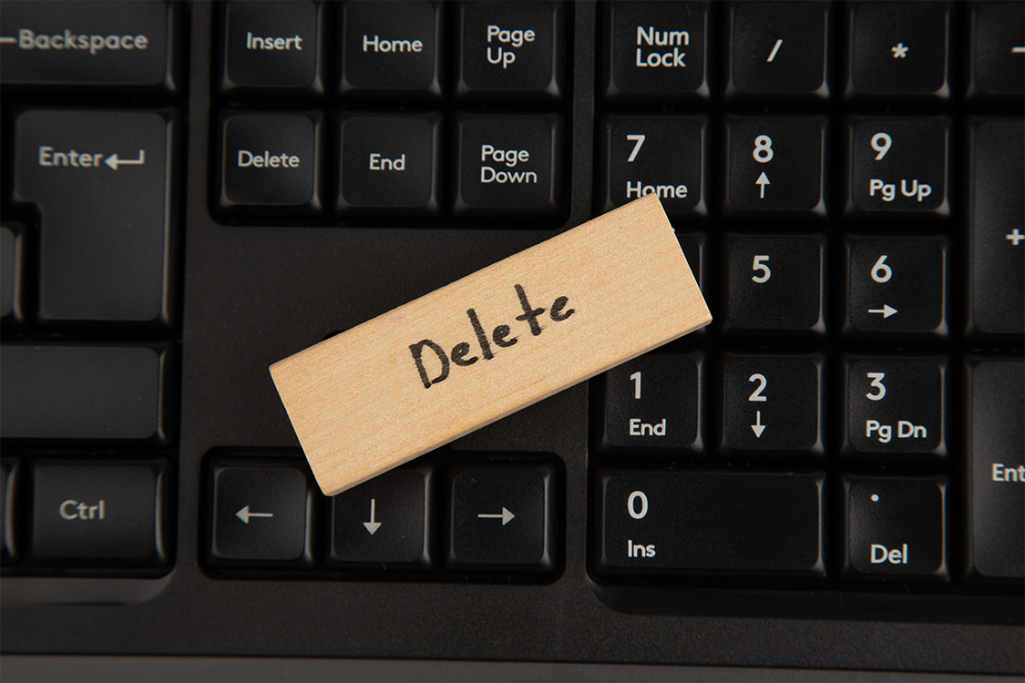 Auf einer Computer Tastatur liegt ein Holzstück auf dem Steht Delete