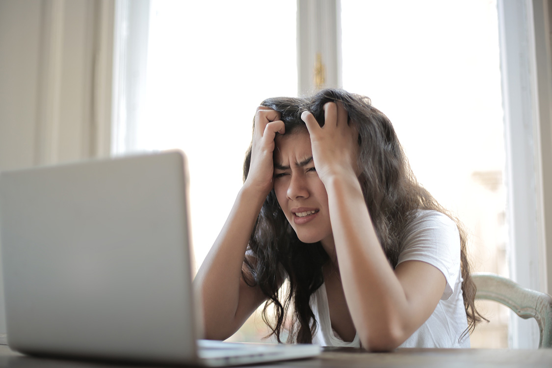 Frau die bedrückt aussieht vor ihrem Laptop