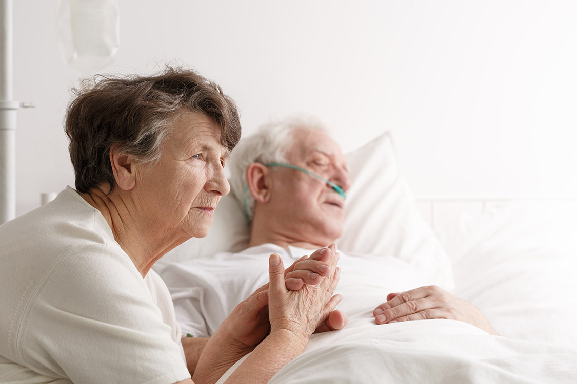 Ein altes ehepaar und der Mann liegt im Sterbebett