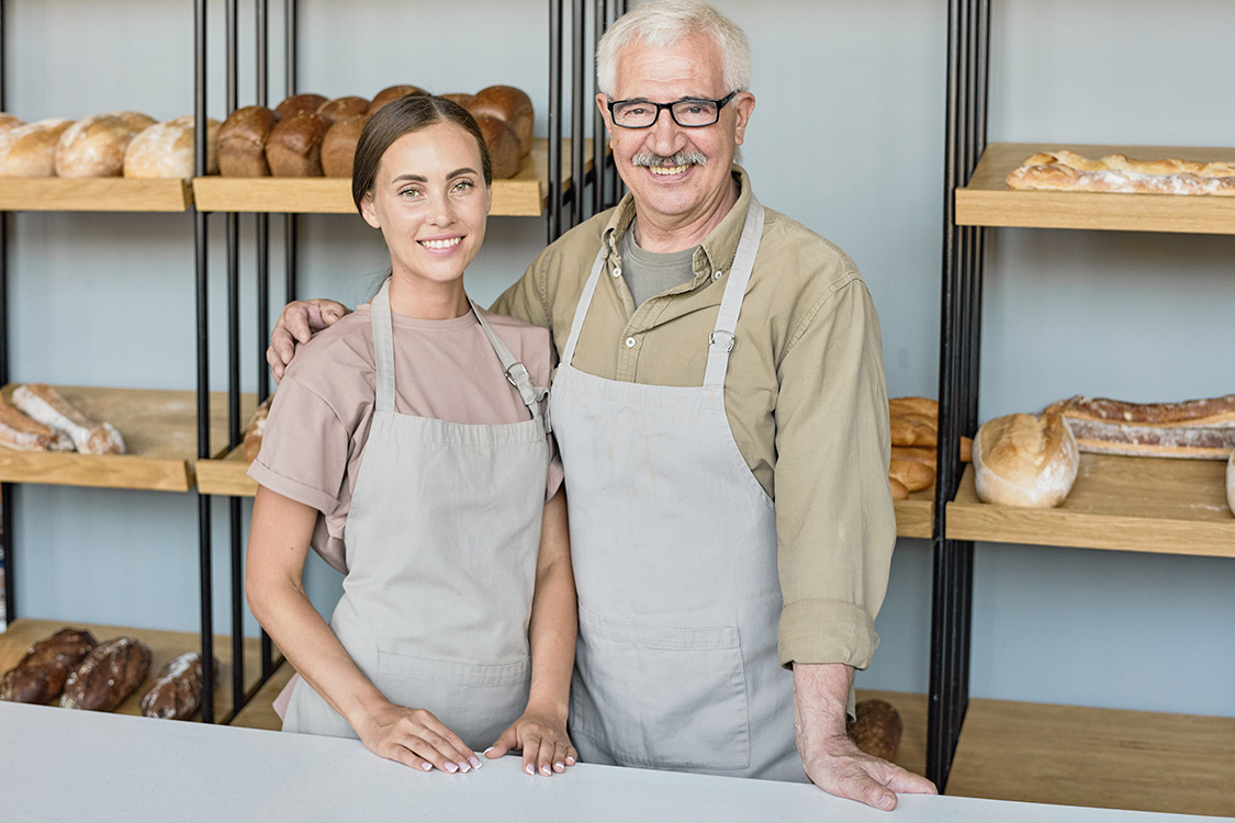 Eine Frau und ein Mann die bei der Verkauftheke im Bäcker stehen