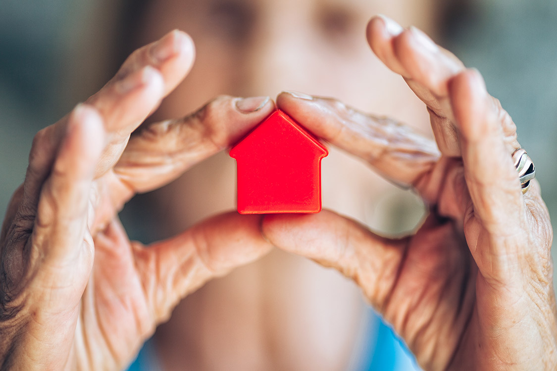 Frau hält rotes mini Haus